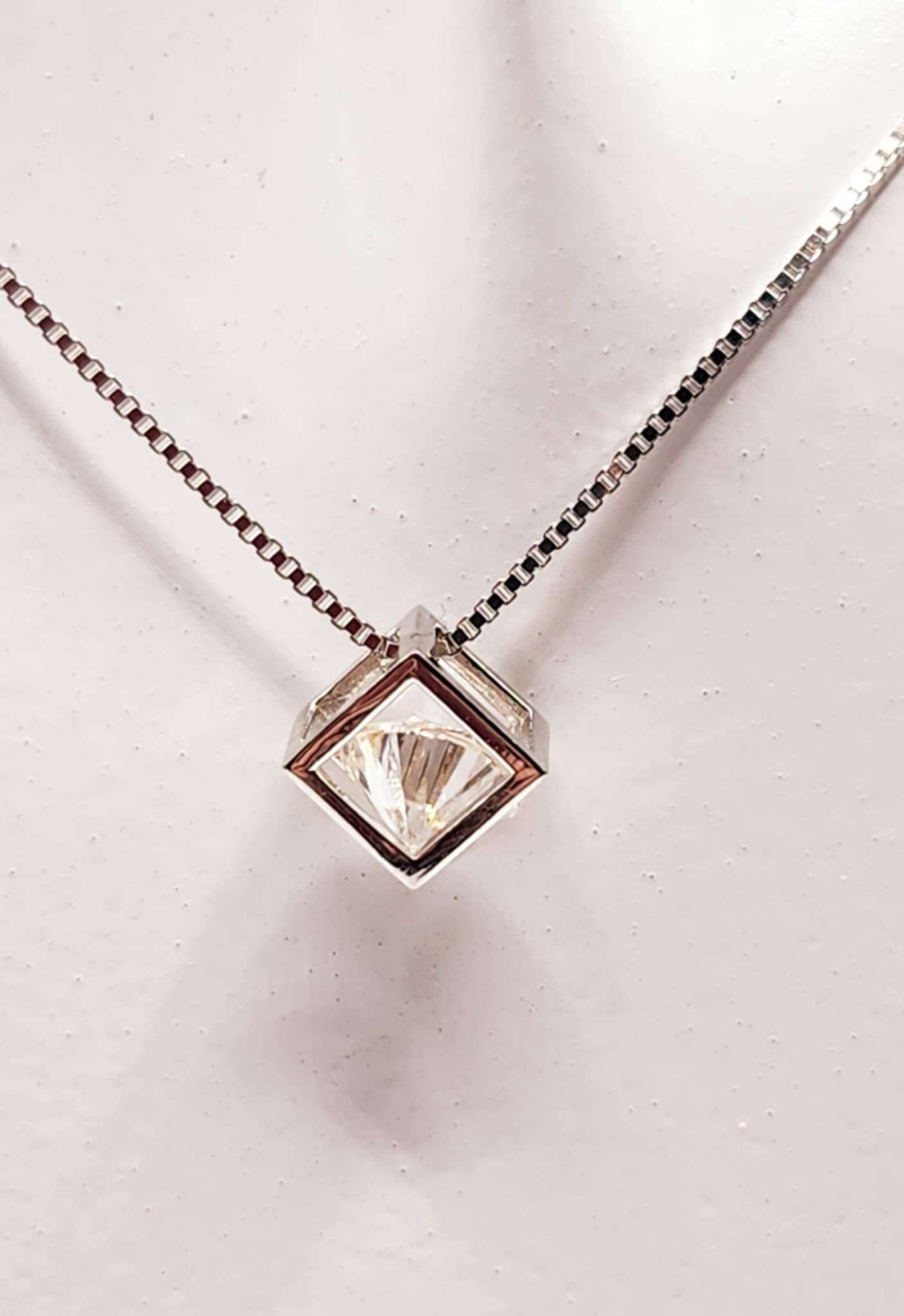 Open Cube Wrapped Solitaire Moissanite Necklace in Sterling Silver with a round cut moissanite stone.