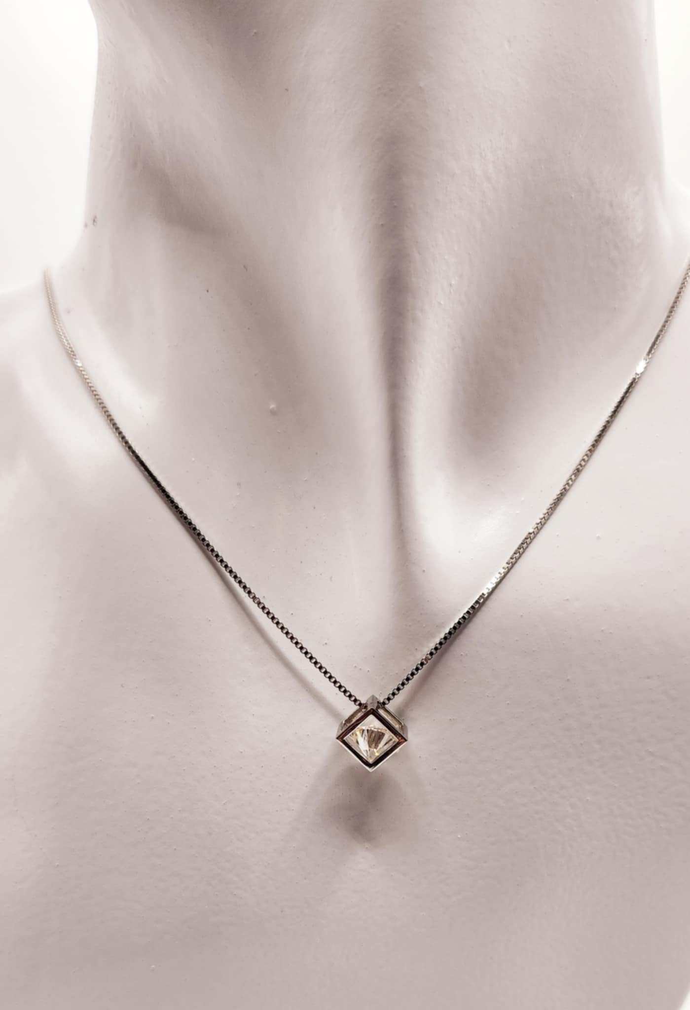 Open cube wrapped solitaire moissanite necklace in sterling silver on display.