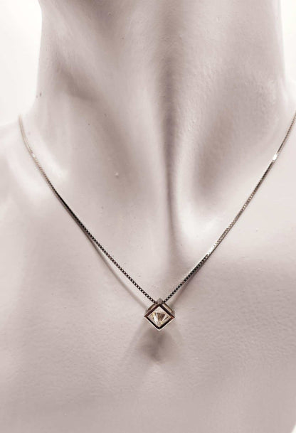 Open cube wrapped solitaire moissanite necklace in sterling silver on display.