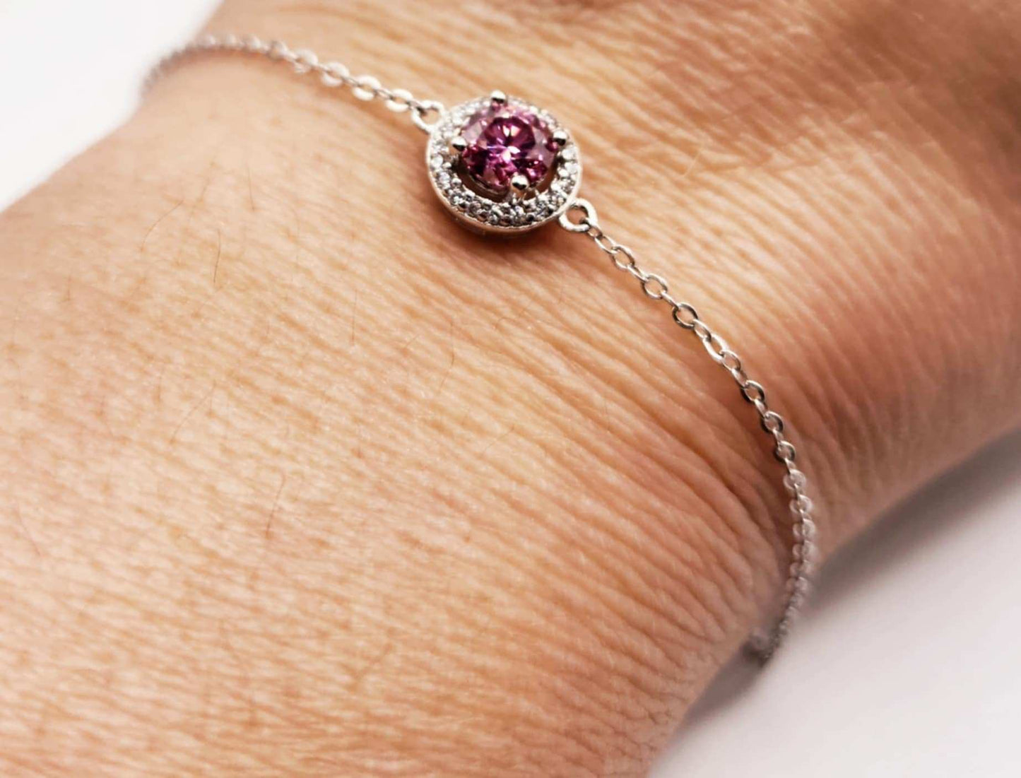 Sterling silver bracelet with round pink sapphire gemstone and halo design.